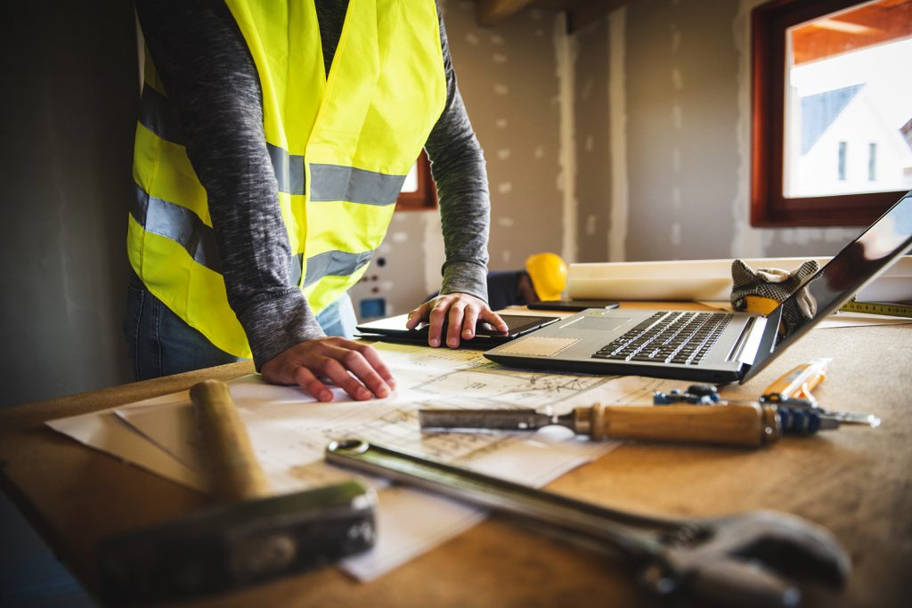Construction Worker Examining Their Plans On A Laptop