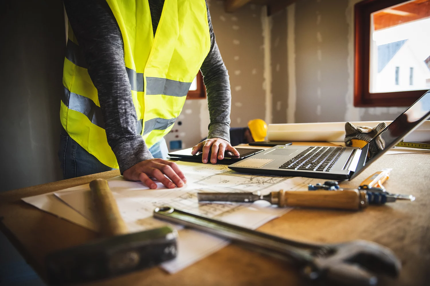 Construction Worker Examining Their Plans On A Laptop